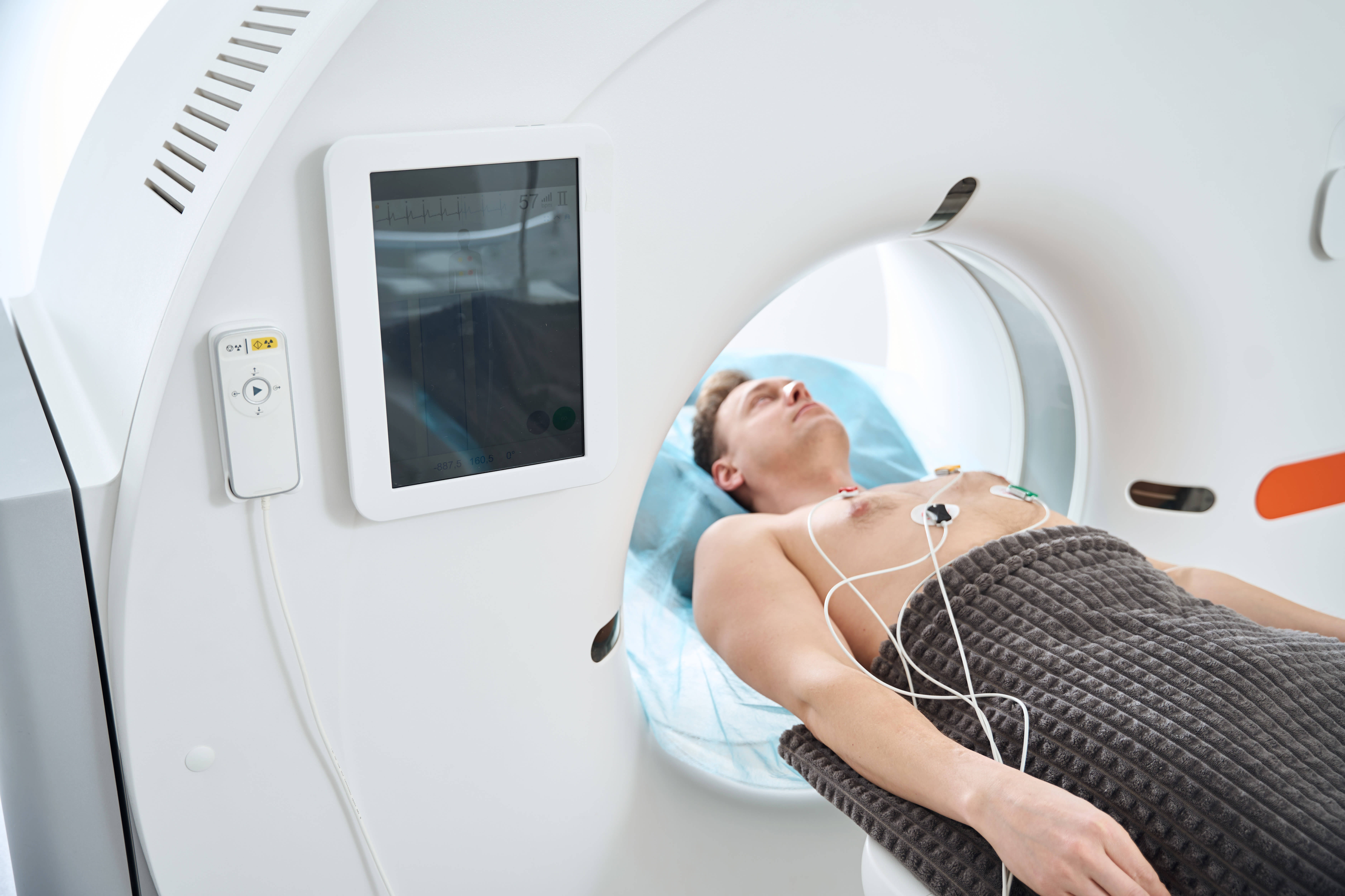 a man getting a ct scan of his heart with electrodes and wires on his chest