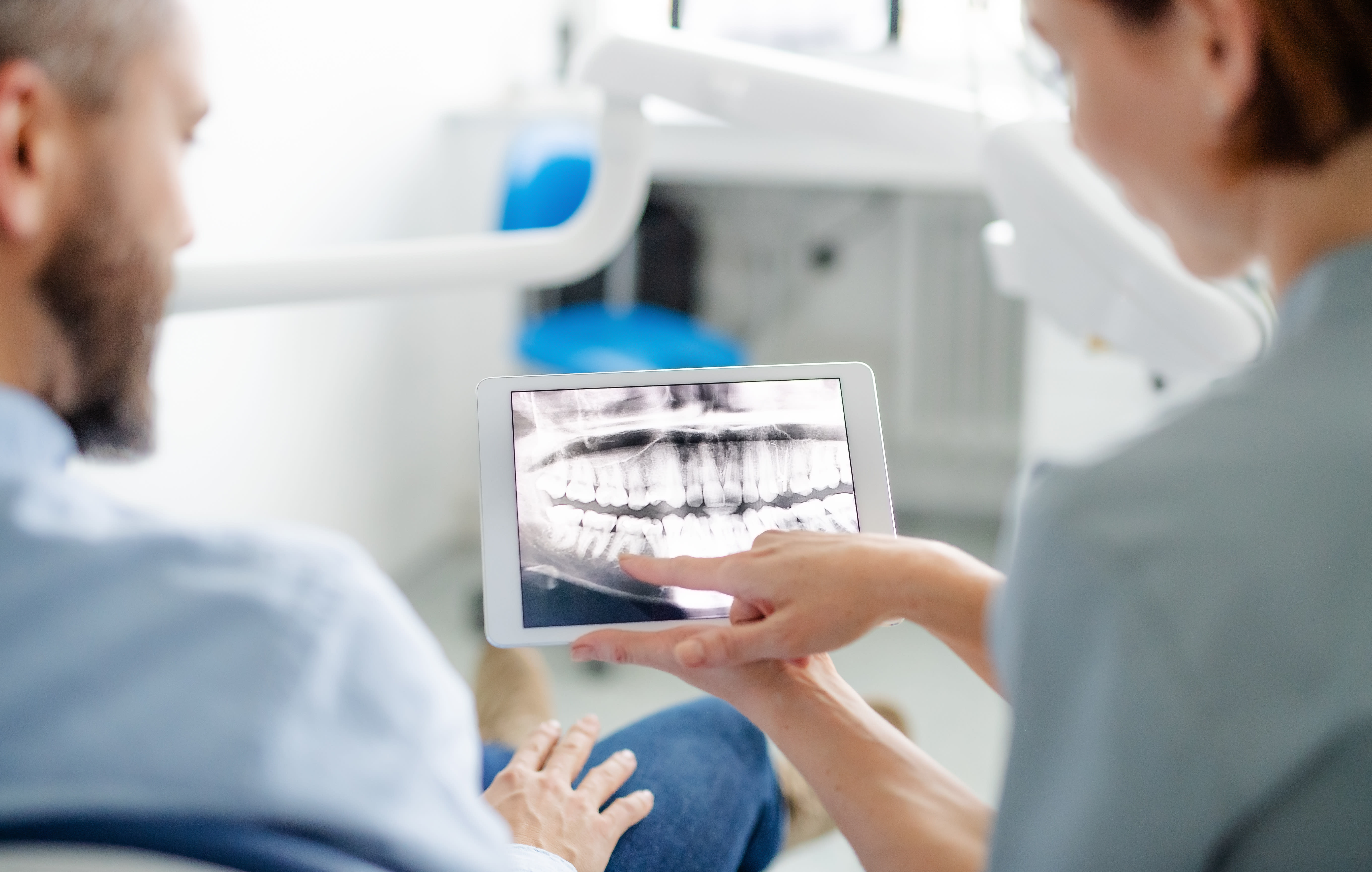 Dentist showing a patient their OPG dental X-ray on a tablet in a dental clinic.