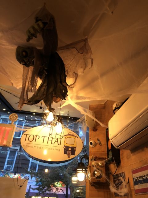 restauarnt interior decorated for Halloween with a ghoul hanging from the ceiling, fake spiderwebs, and a skull atop an air conditioner