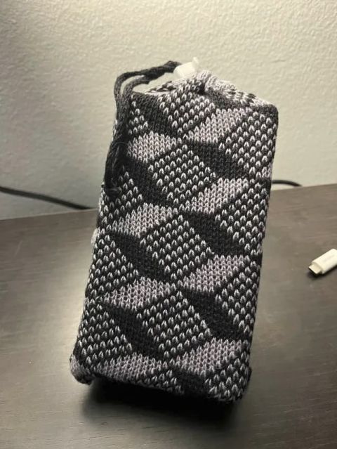 Bag with test-brick inside posted on a black desk top. The black ccord and lace lock cinch the top closed.