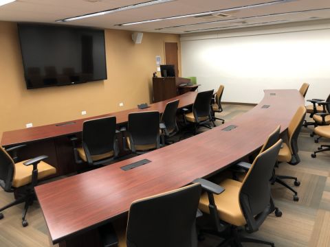 a conference room with two large curved tables facing a large television