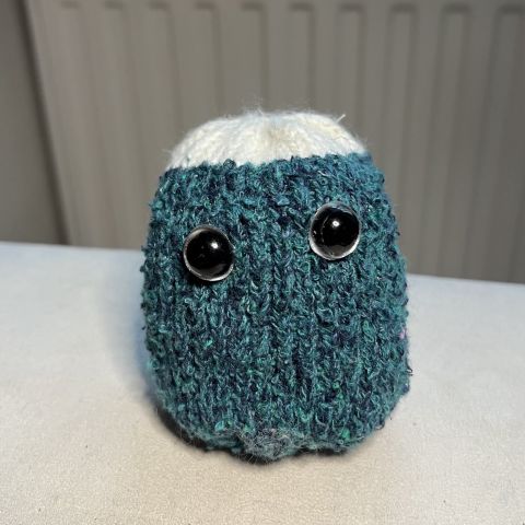 Round little guy with a fuzzy green body, white hair, and silver safety eyes.