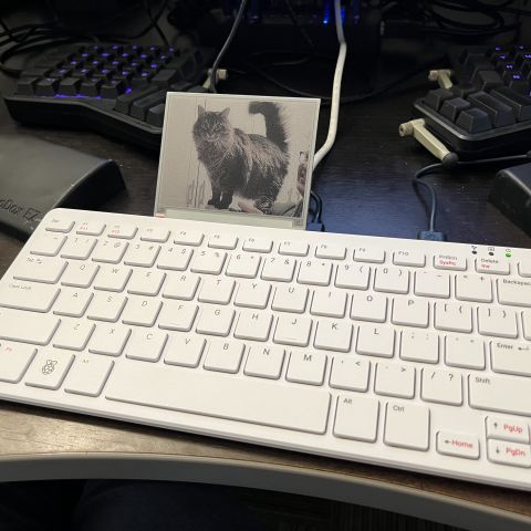 RaspberryPi 500 keyboard with small eInk screen attached. A cat is displayed on the screen.