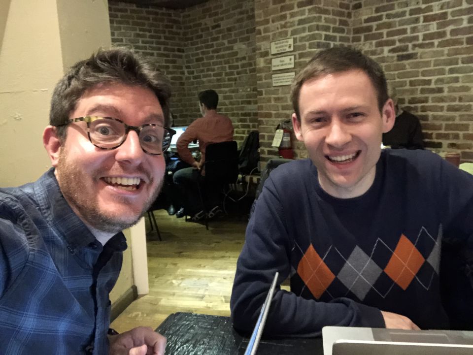 Marty and Dmitri smile at the camera, sitting in front of a brick wall.