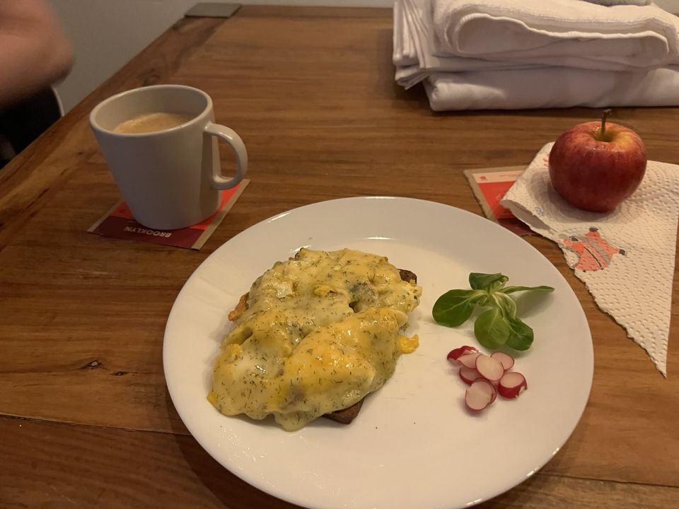 A breakfast spread with an open face egg sandwich, tiny salad, coffee, and apple.