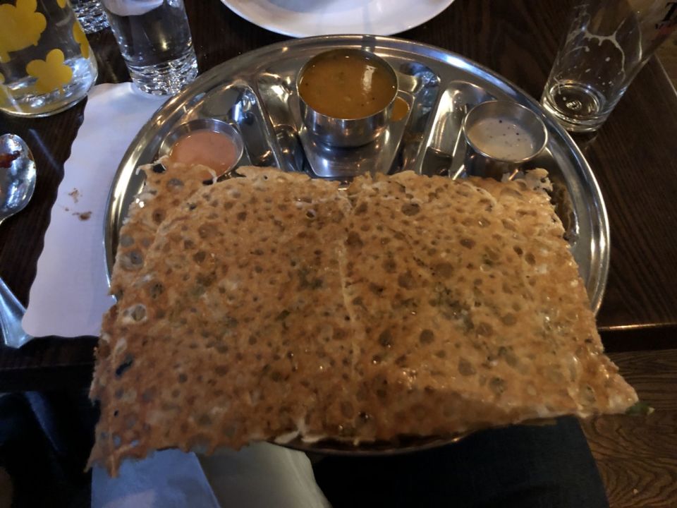 a large dosa on a small circular metal tray