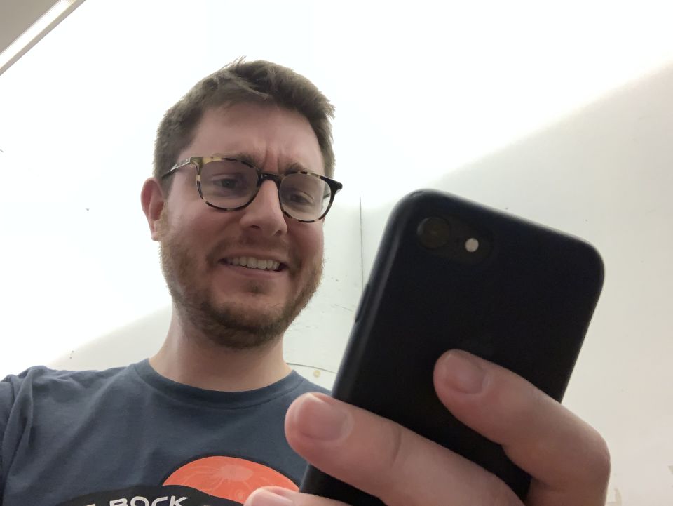 Marty makes a quirky grin while staring into his phone