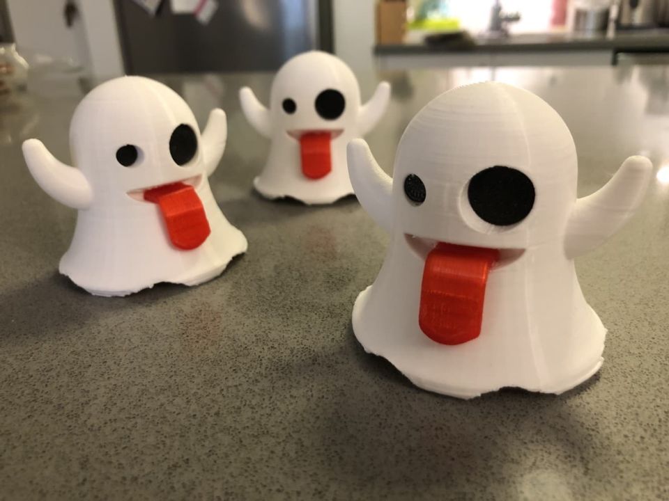 Three finished 3D-printed Ghost Emoji figurines arranged on a grey countertop.