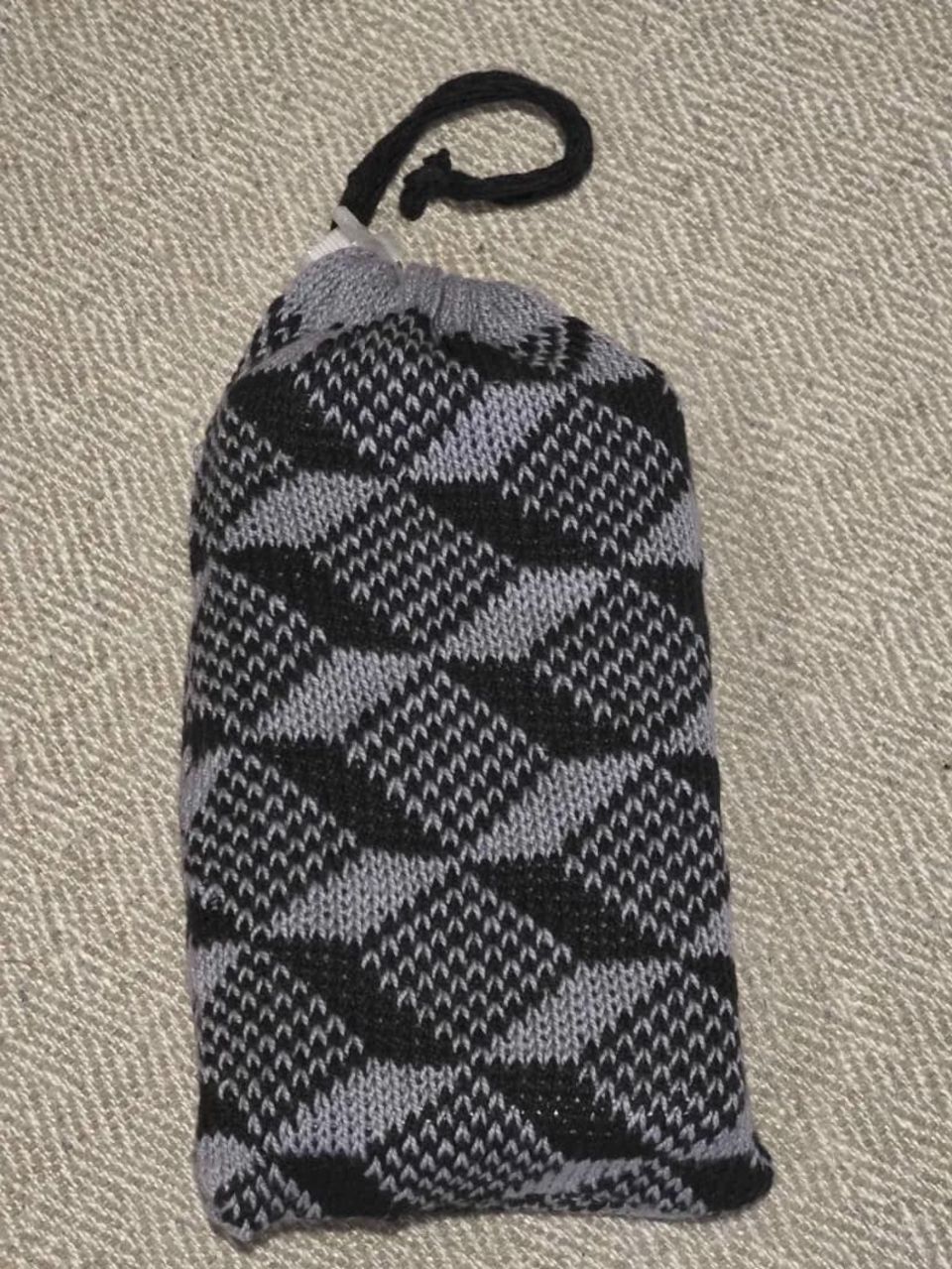 Cinched bag with brick inside resting on a patterned surface.