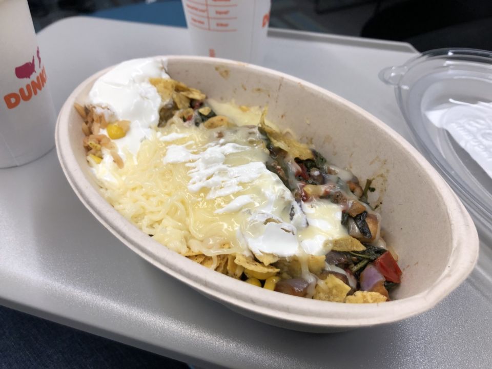 a cardboard container filled with beans, rice, vegetables, cheese, and sour cream