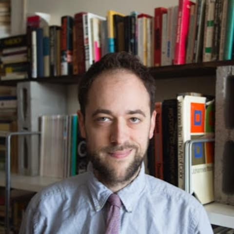 Headshot of Prof. Jeremy Cohan, in front of bookshelf