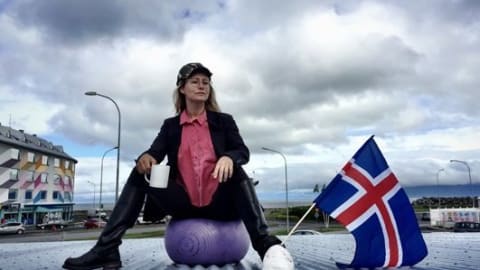A woman sitting on a ball with a flag near her foot