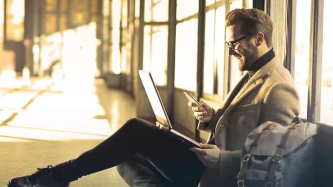 smiling holding a smartphone a laptop