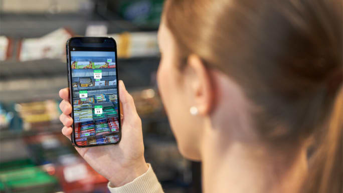 Grocery shopper using automated data capture on a smartphone to compare products on shelf.