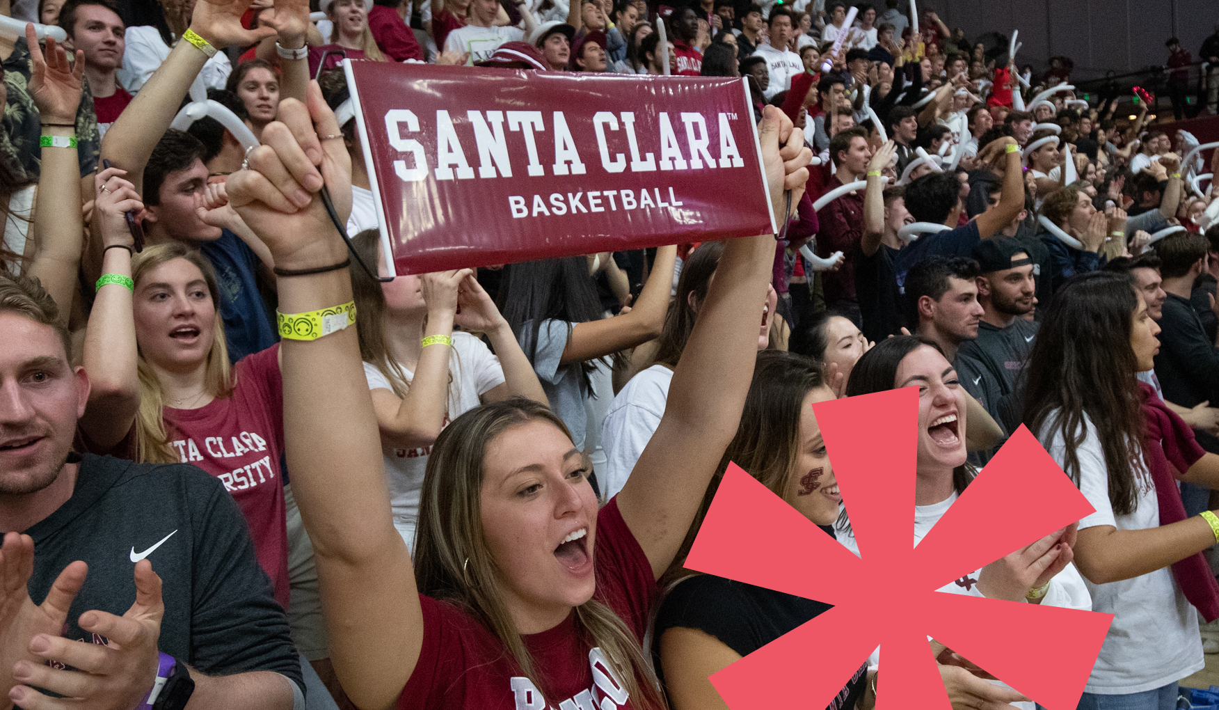 A crowd of enthusiastic Santa Clara University students cheering at a basketball game. One student is holding up a sign that reads 'SANTA CLARA BASKETBALL'.