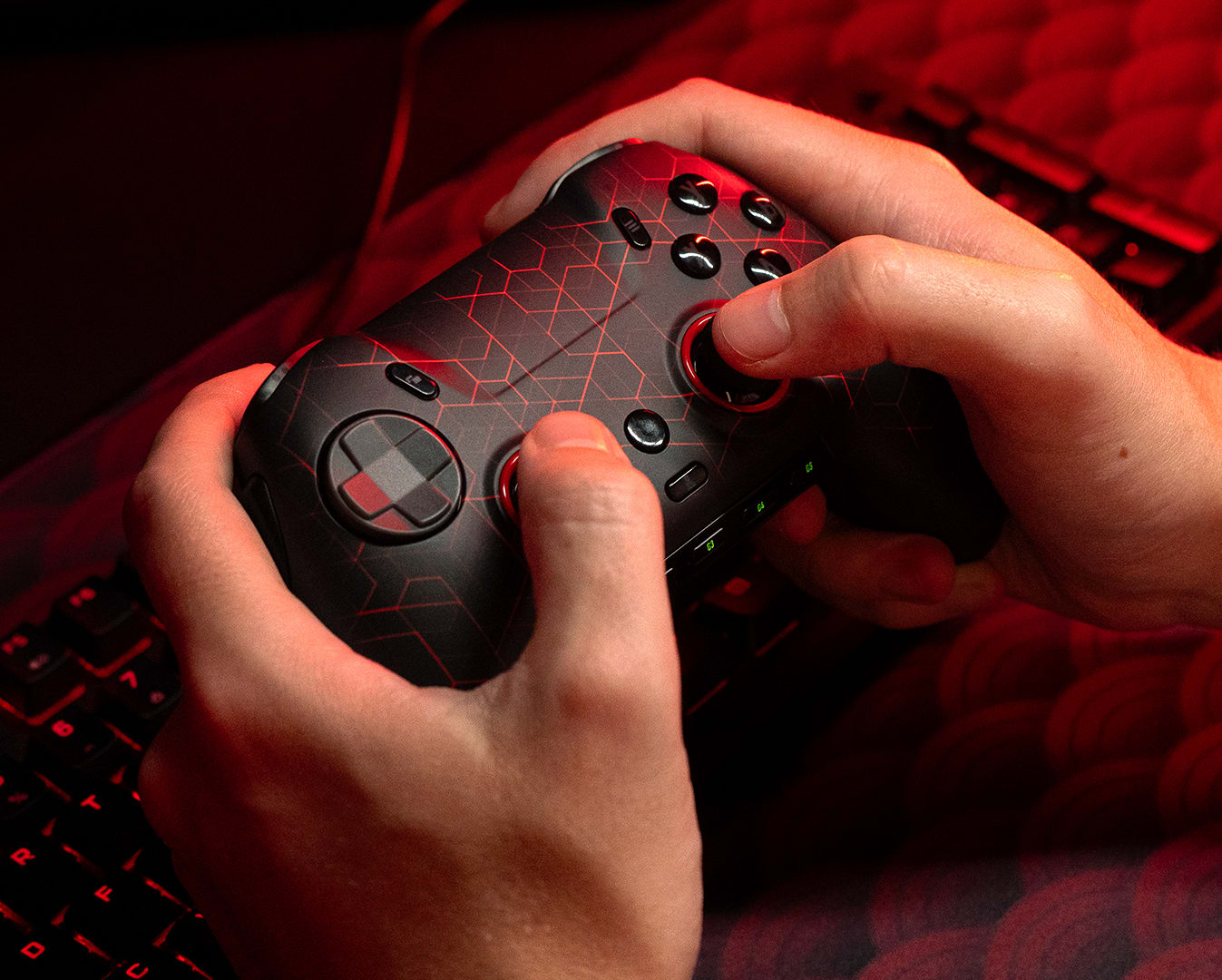 Hands holding a custom gaming controller with a red background light for ambience.