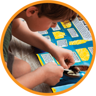 boy placing a sticker on an activity book boy placing a sticker on an activity book