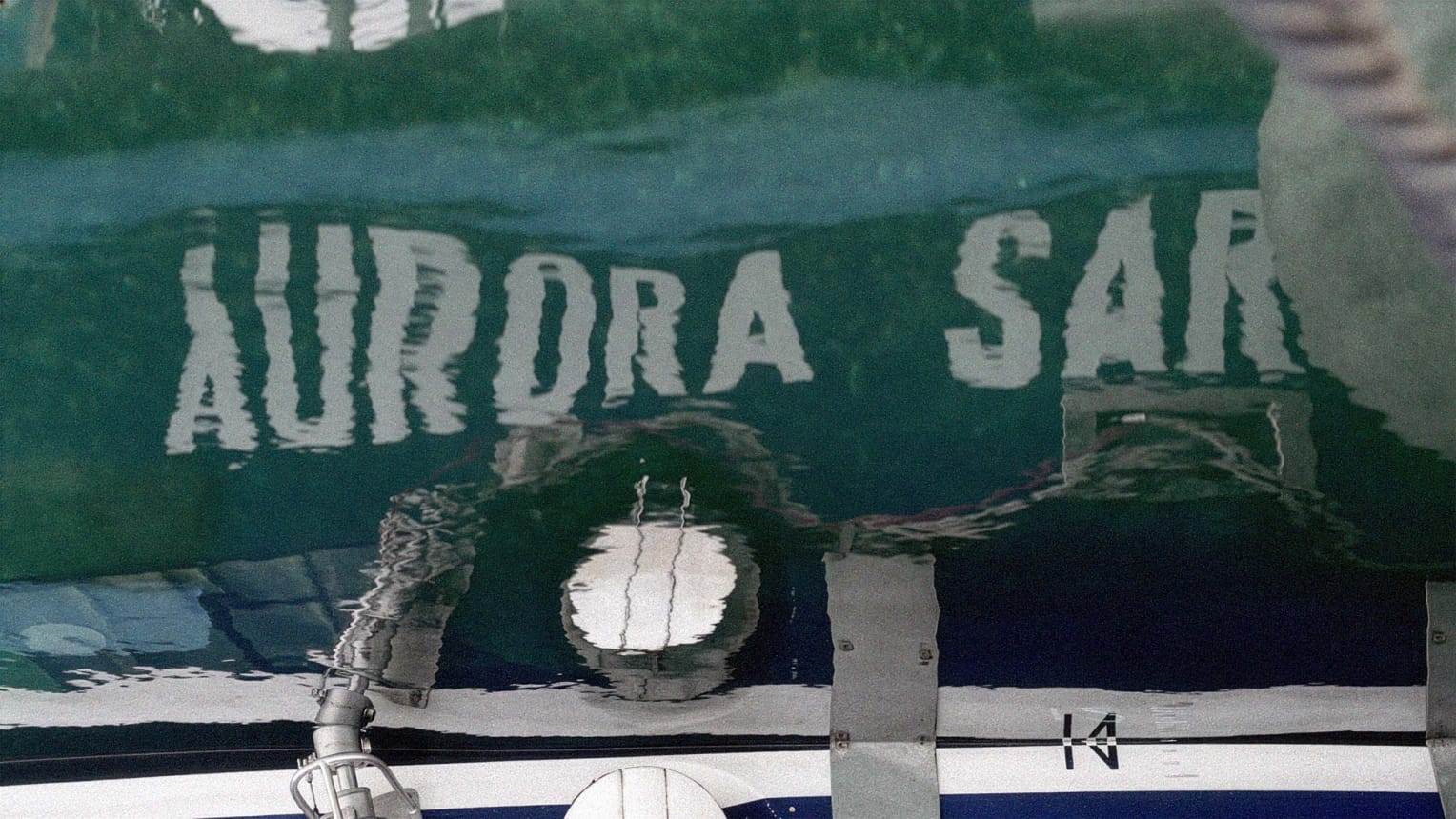 Der Schiffname Aurora 2 am Rumpf gespiegelt im Wasser.