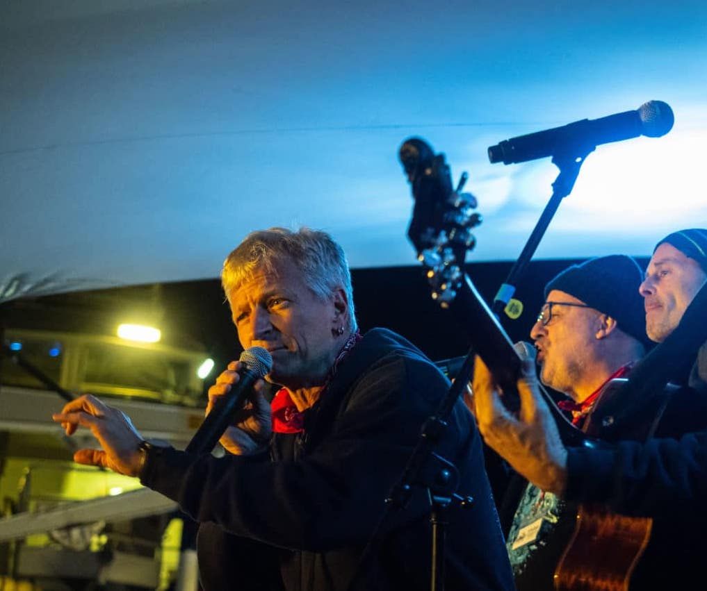 Musiker mit Mikros und Gitarren auf einer Bühne