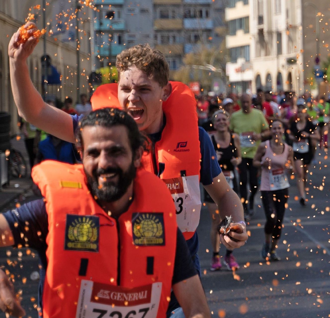 Menschen in Rettungswesten laufen einen Halbmarathon und werfen dabei Konfetti.