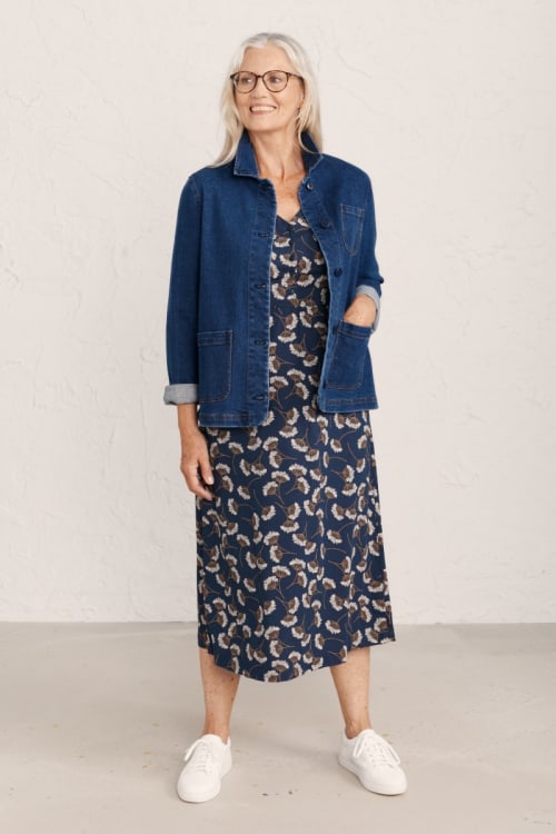Mature woman wearing a denim jacket over a patterned blue midi dress