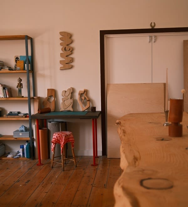 A shot of a small desk next to a large table in Jess's space, with a small stool next to it