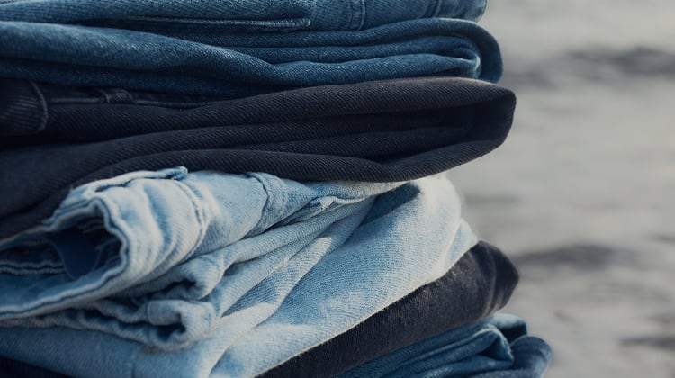A stack of Seasalt jeans in different washes on the beach