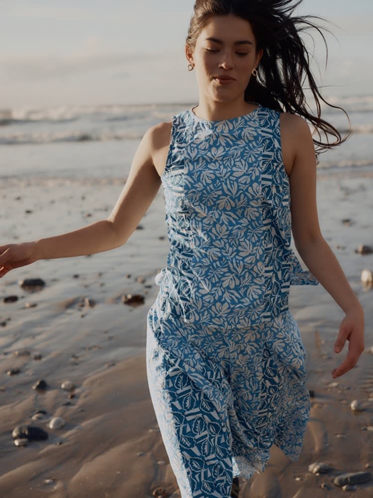 Model at beach runs wearing both the Camomile Vest and Skirt in a patchwork of blue pattern