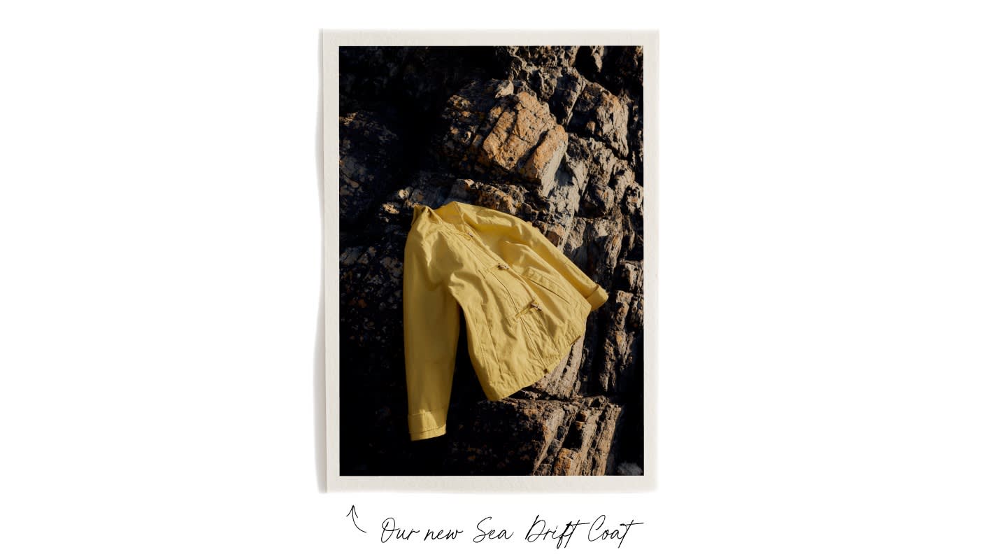 The yellow Seasalt Sea Drift coat on some rocks