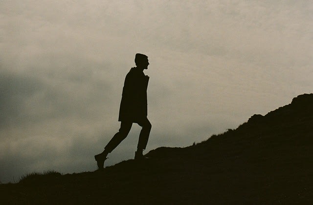 A silhouette of a man walking uphill wearing Seasalt rainwear