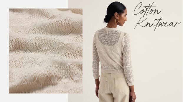 A female model wearing a white pointelle stitch jumper knitted with organic cotton.