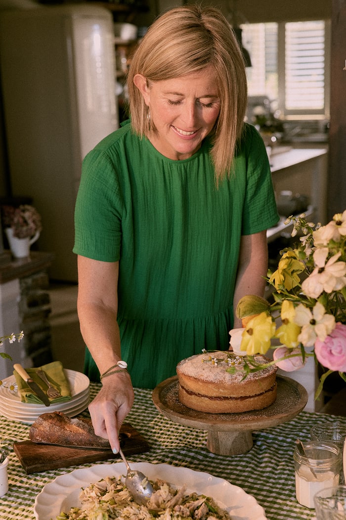 Emily Scott serves dinner in her Cornish kitchen. She wears a green dress from Seasalt Cornwall