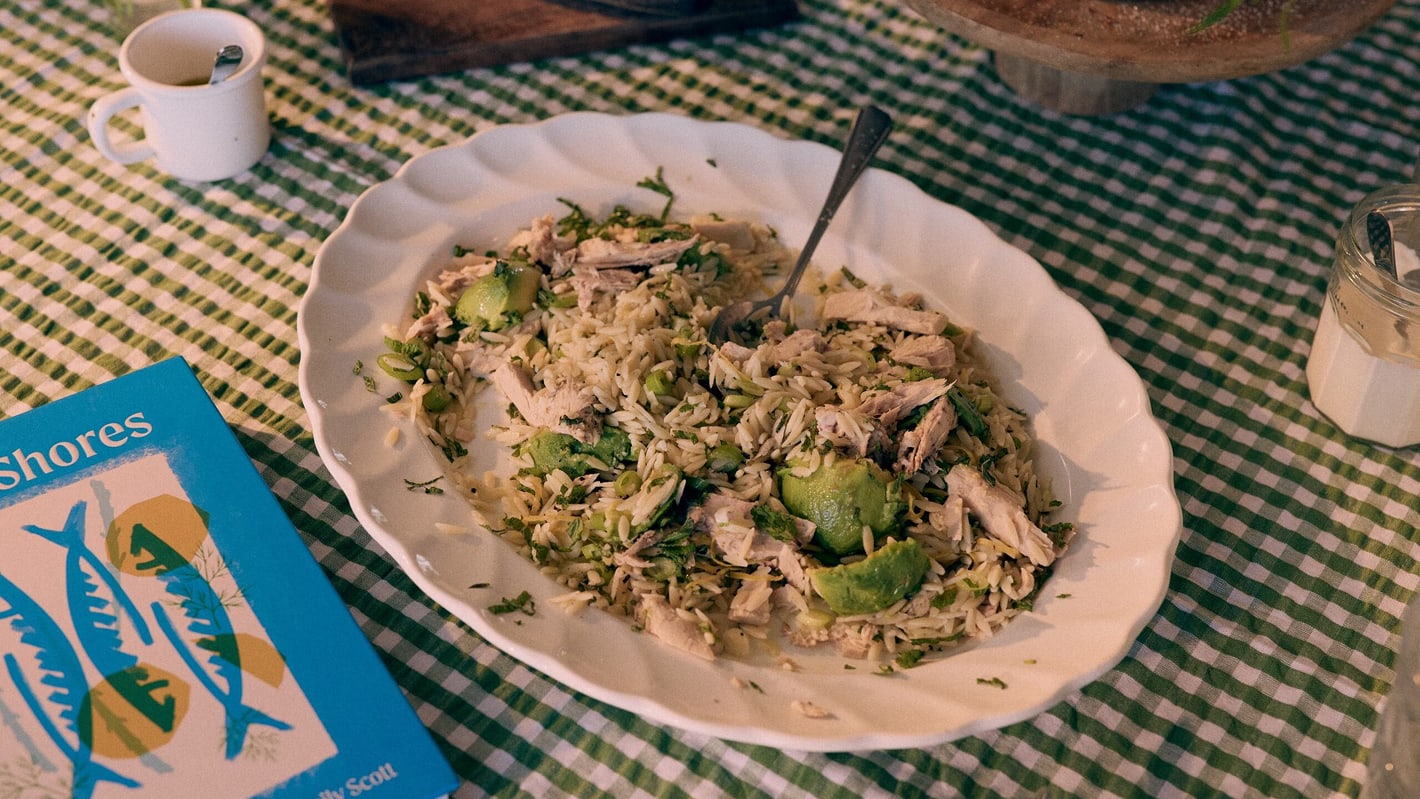 Freshly prepared lemony orzo pasta in a white serving bowl on top of a gingham table cloth
