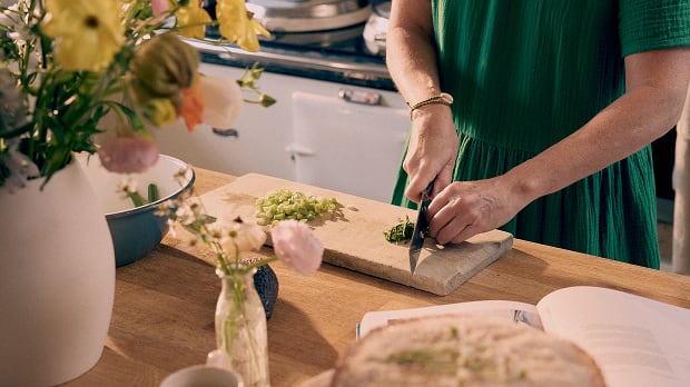 Emily Scott chops herbs on a wooden cutting board