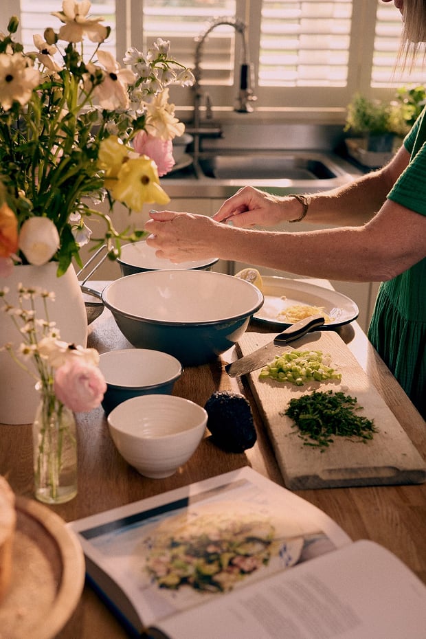 Emily Scott prepares dinner, putting food into various sized blue bowls.