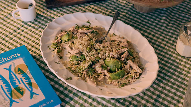 Freshly prepared lemony orzo pasta in a white serving bowl on top of a gingham table cloth