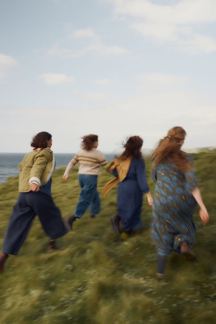 Four members of Femmes De La Mer wearing Seasalt and running across the cliffs