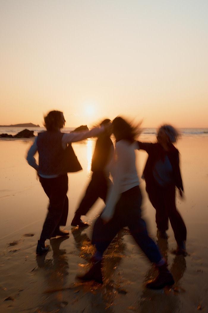 Members of Femmes De La Mer spinning on the beach at sunset