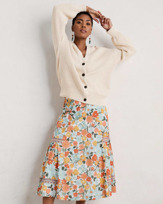 A woman wearing an ecru knitted cardigan and a floral maxi skirt