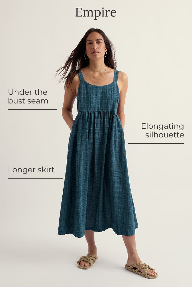 A model wears a sleeveless empire line dress in navy blue gingham