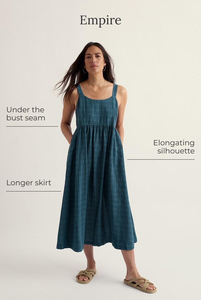 A model wears a sleeveless empire line dress in navy blue gingham