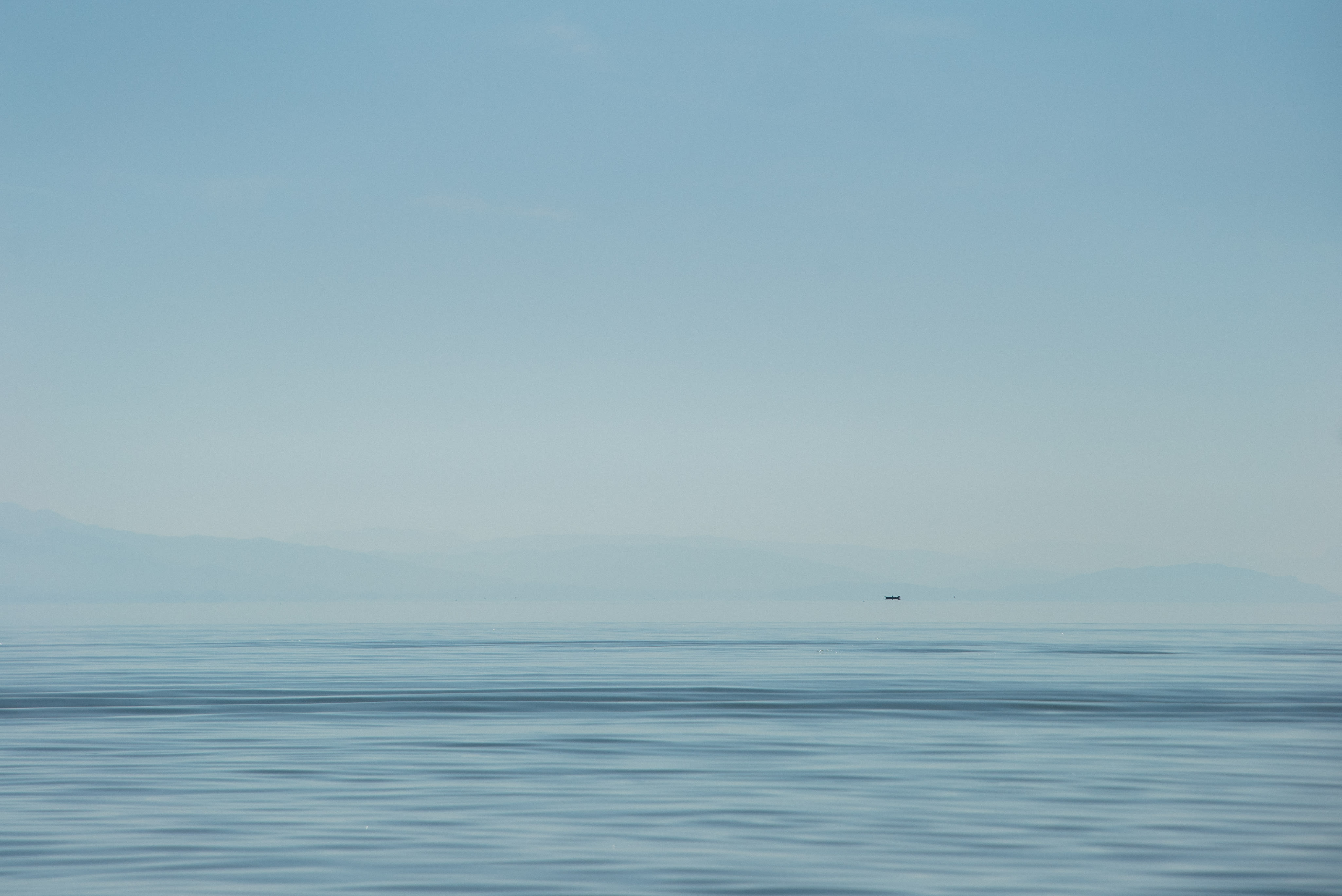 A large body of water sitting under a blue sky.