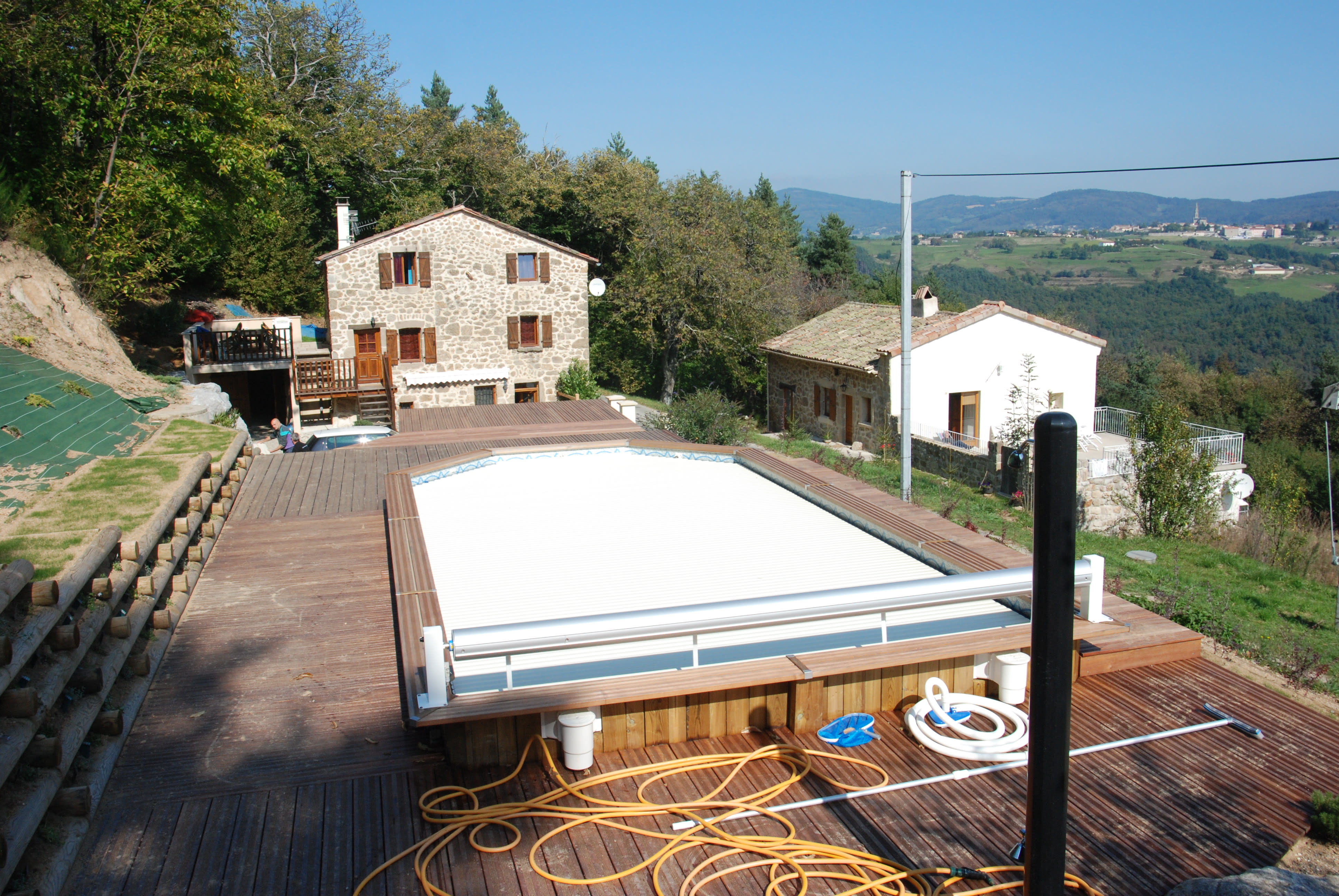 Deck en bois autour d'une piscine avec système de couverture