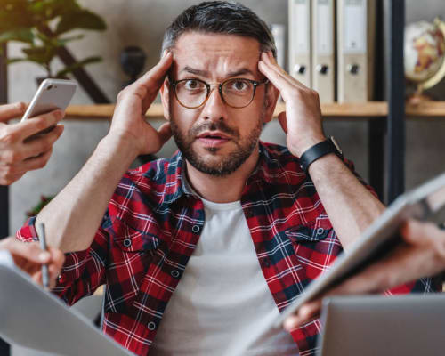 un slasheur se prend la tête face à trop de sollicitations, devant lui on peut voir des smartphones et des tablettes