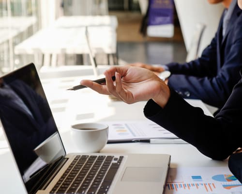 Personnes en réunion autour d’un ordinateur portable avec des documents financiers