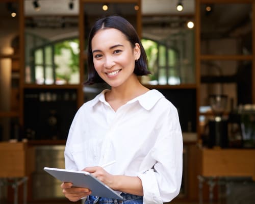 Femme souriante tenant une tablette numérique dans un café ou restaurant moderne