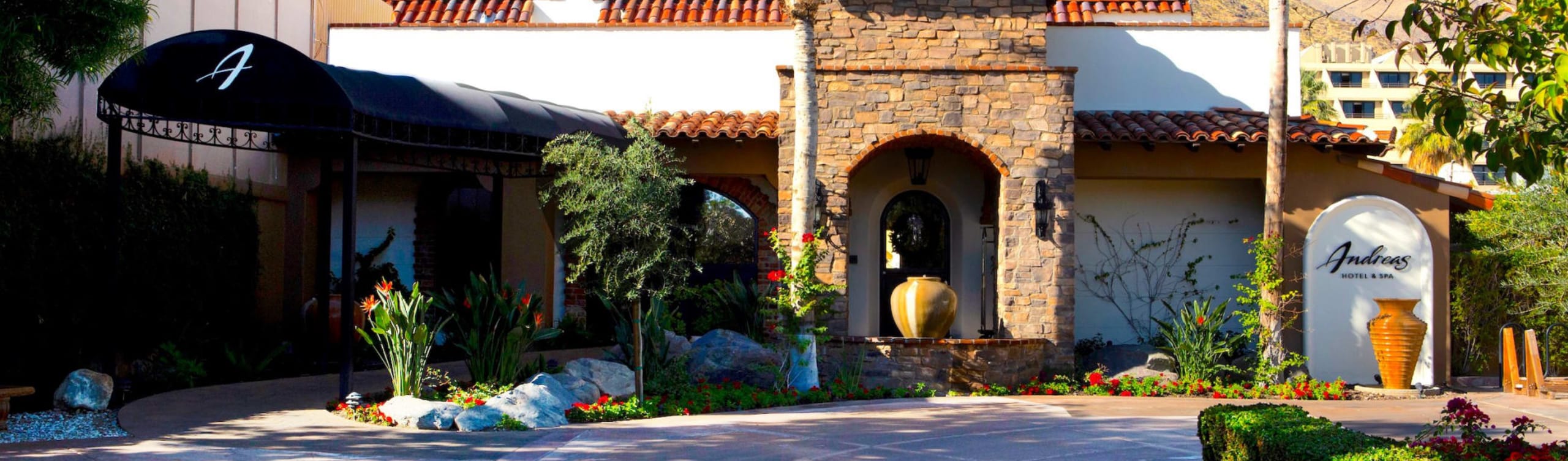 The façade of a hotel with stonework, archways, and a sign reading 'Andreas Hotel & Spa'.