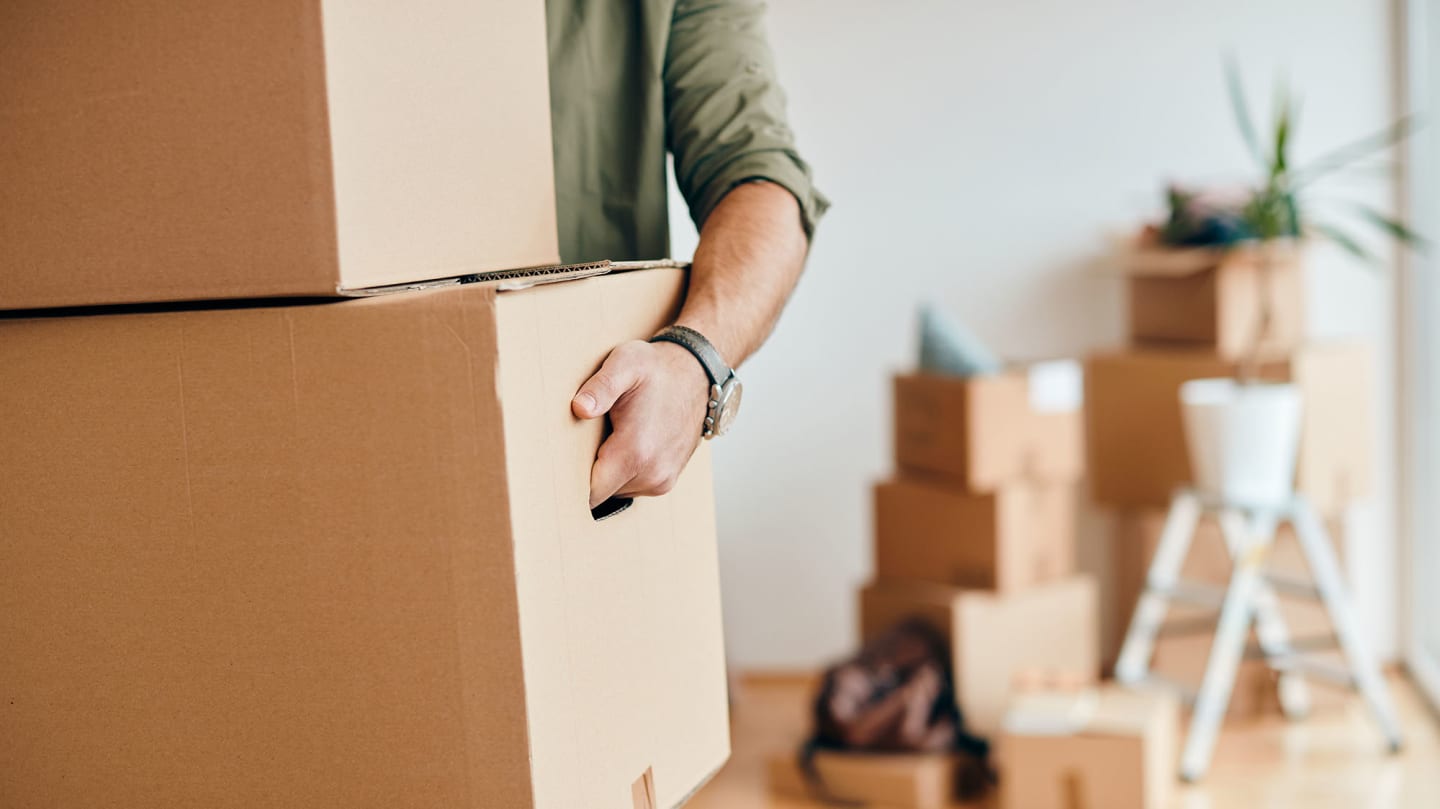 A young adult organizing belongings in a clean, furnished transitional housing apartment.