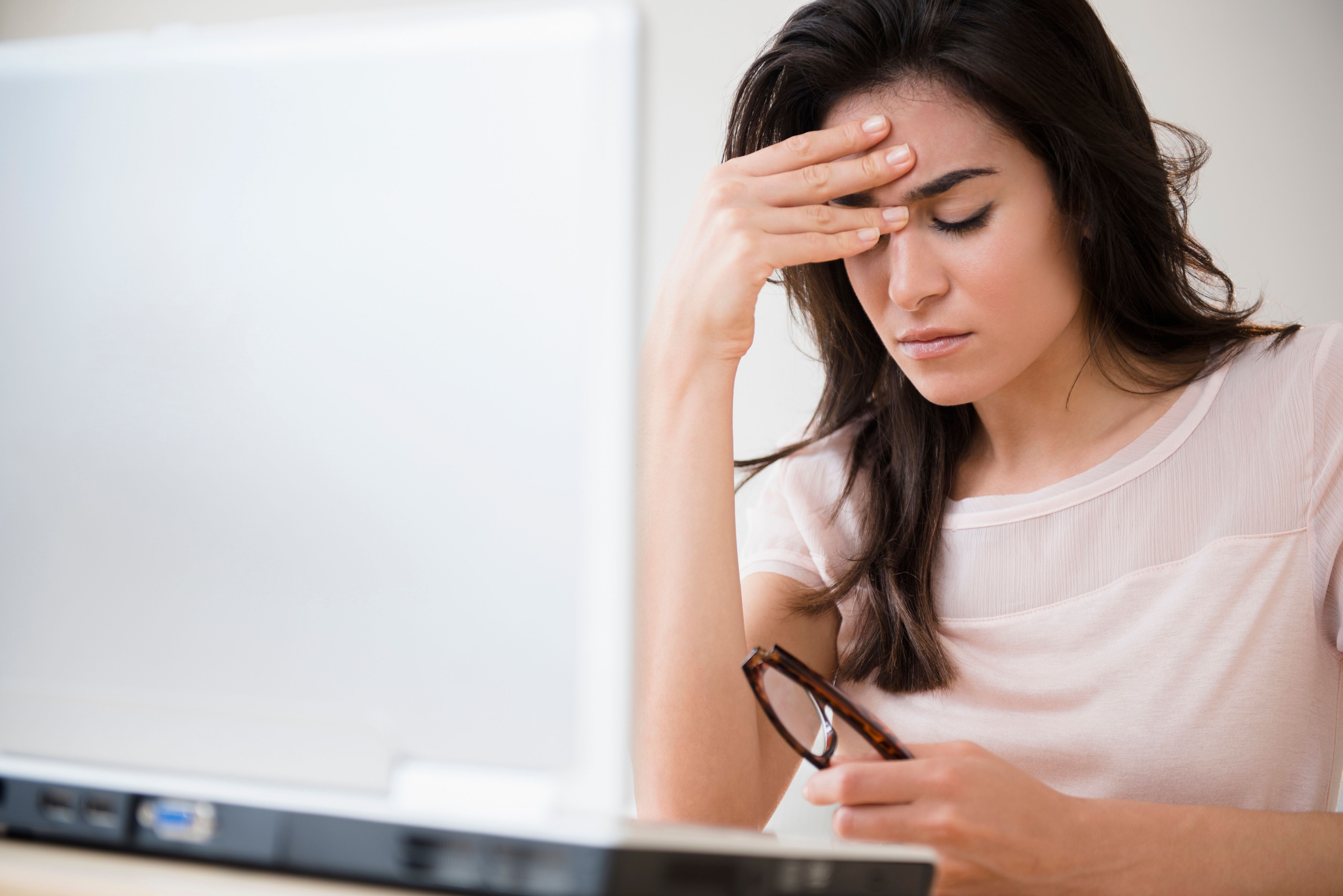 Woman holding her head in front of her computer