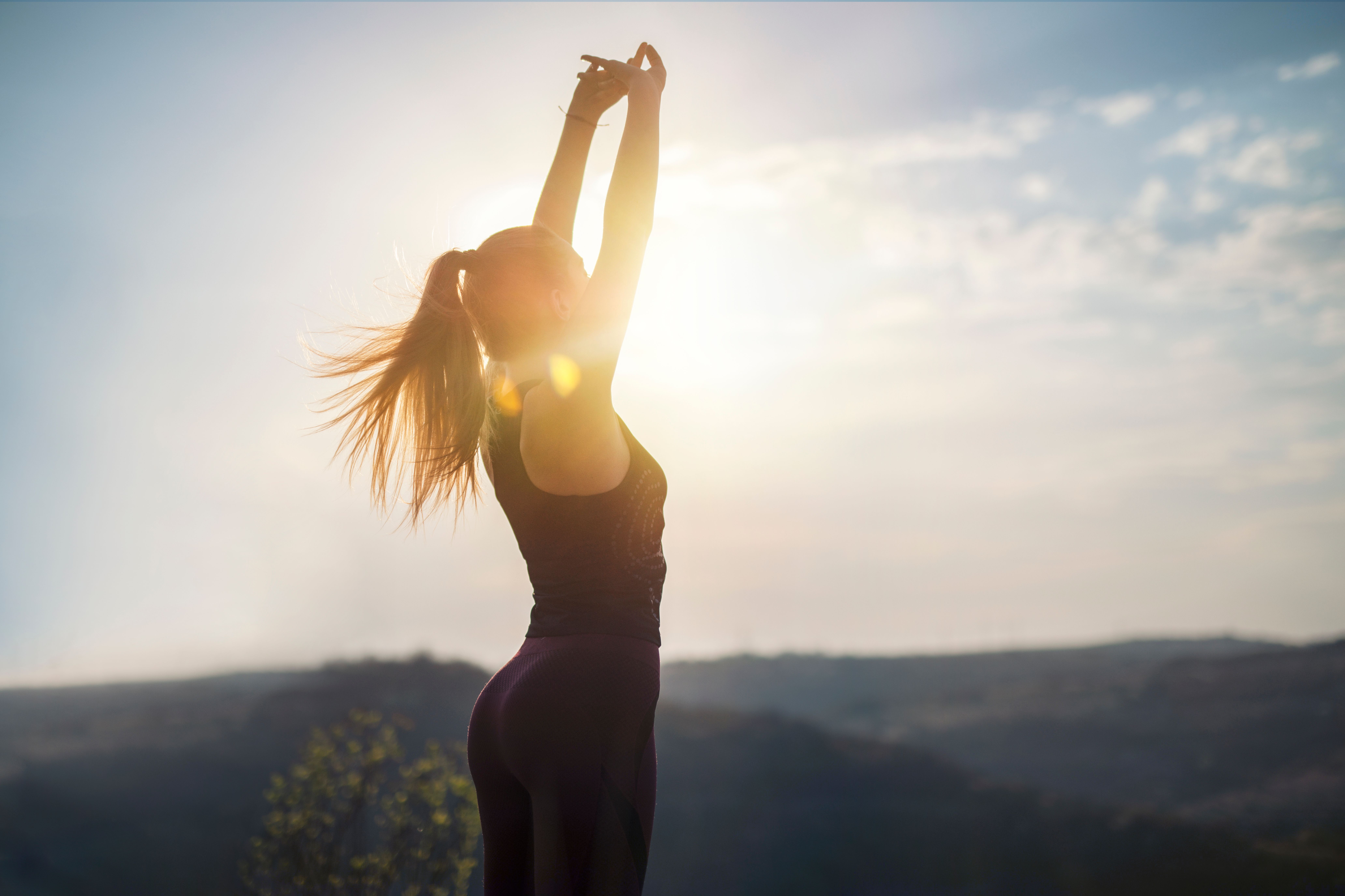 woman stretching on top of mountain by dawn